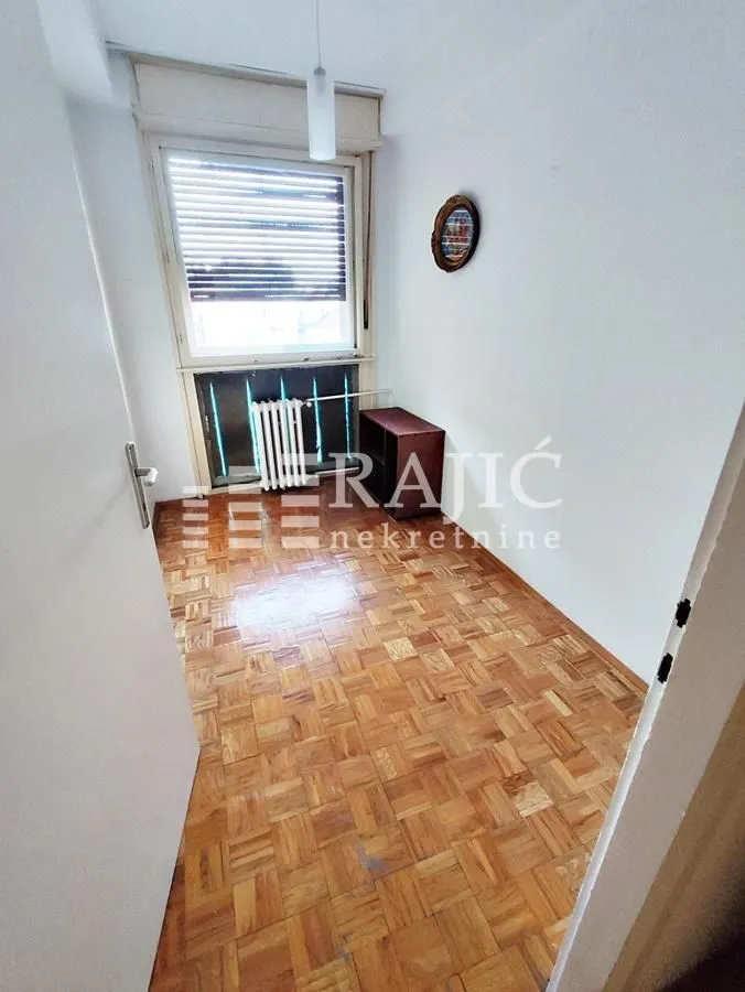 Small empty room with parquet flooring and a window.