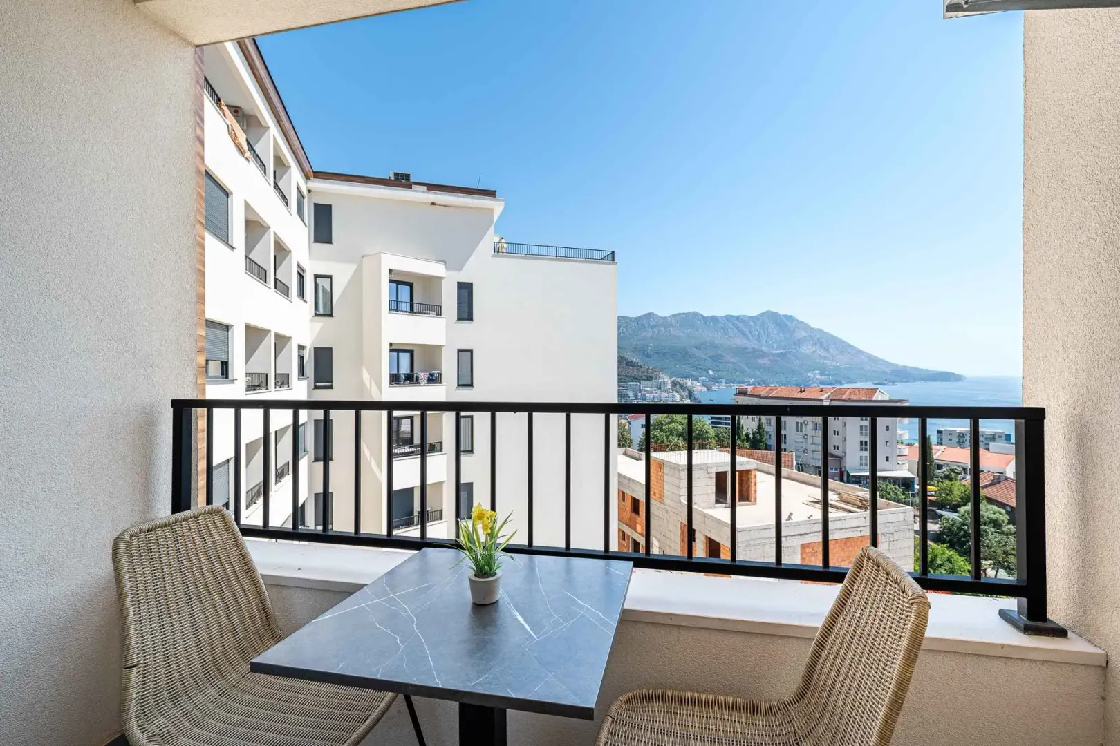 Namješten balkon sa stolom, stolicama i pogledom na more.
