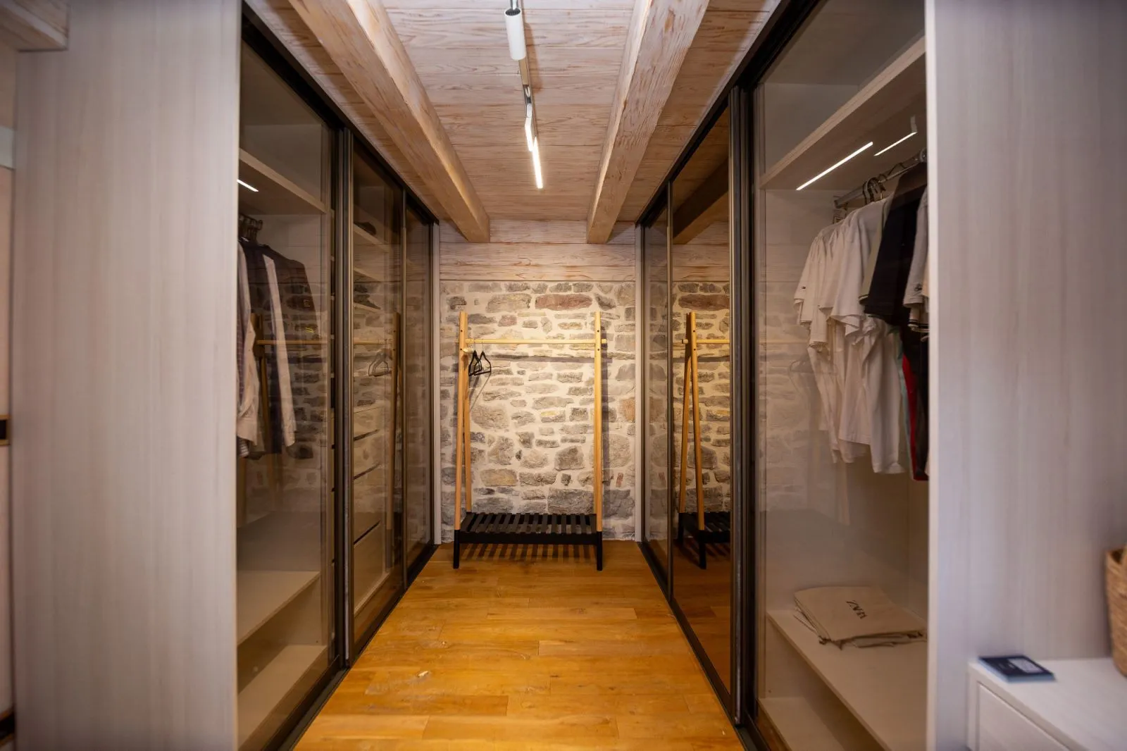 Modern walk-in closet with built-in wardrobes and wooden flooring.