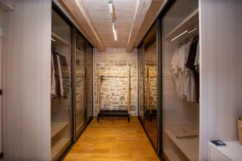 Modern walk-in closet with built-in wardrobes and wooden flooring. - image 4
