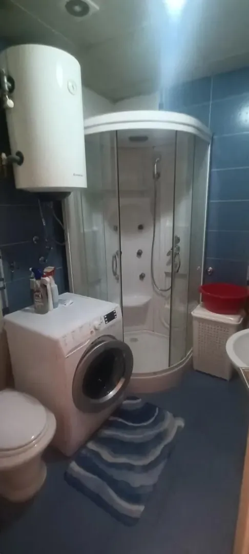 Manje kupatilo sa tuš kabinom, veš mašinom i bojlerom.