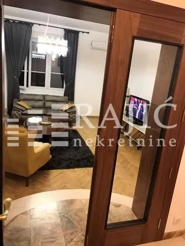 Pogled iz hodnika na dnevni boravak sa garniturom i parketom.