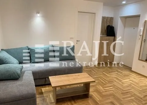 Living room with a sectional sofa, wooden coffee table, and parquet flooring.