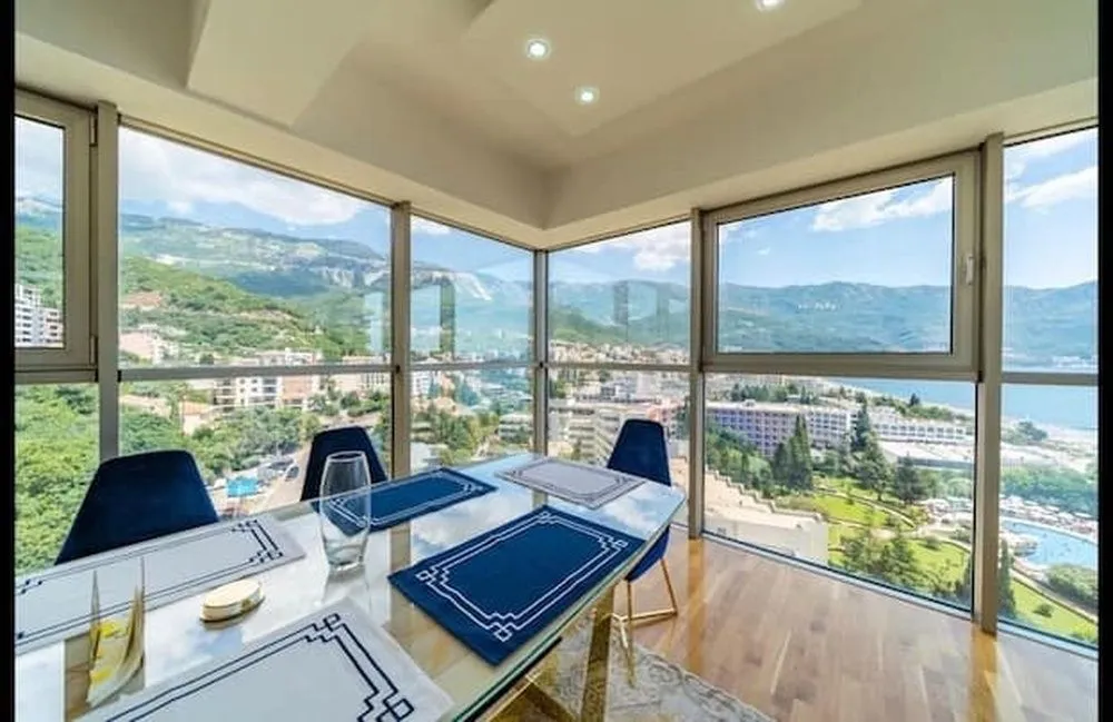 Dining area with large glass surfaces and sea and mountain views.