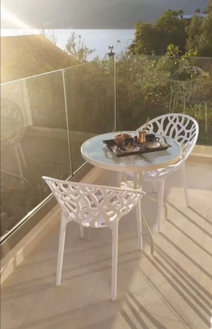 Bright balcony with a table, chairs, and sea view.
