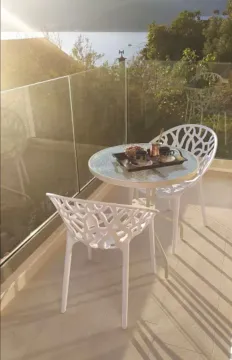 Bright balcony with a table, chairs, and sea view. - image 7