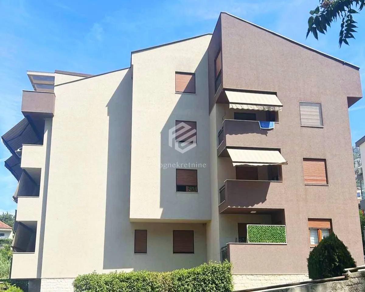 Pogled na spoljašnjost moderne stambene zgrade sa terasam i zelenilom.