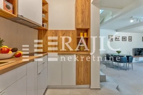 Modern kitchen with white and wooden elements, overlooking the dining area.
