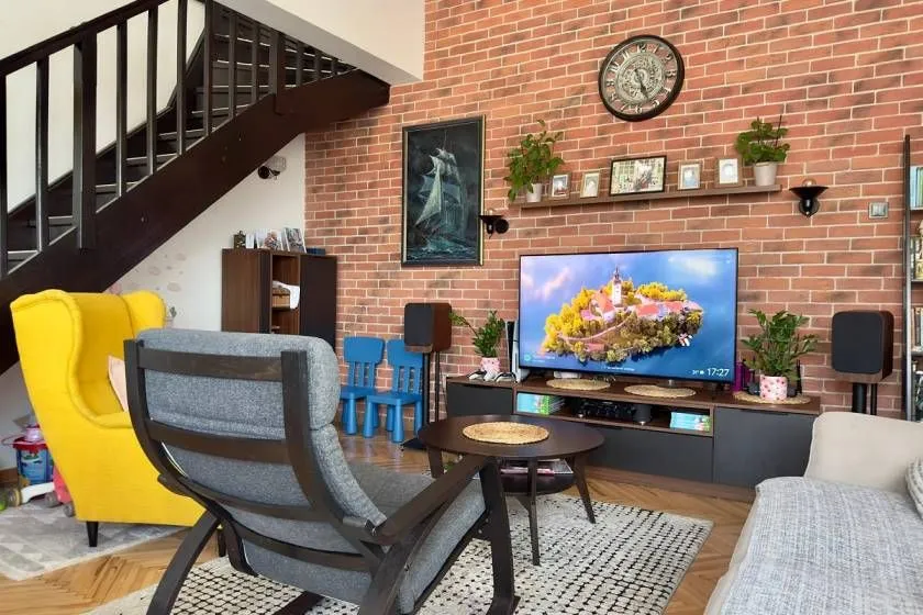 Prostrani dnevni boravak sa garniturom, TV-om i stepeništem.