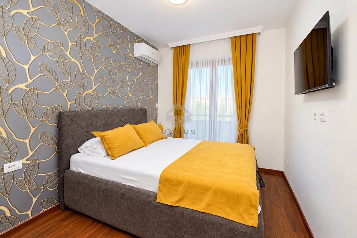 Modern bedroom with a double bed, decorative wallpaper, and an air conditioner.