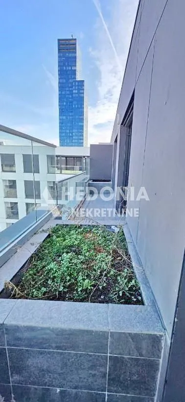 Terasa sa zelenom površinom i pogledom na visoku zgradu.