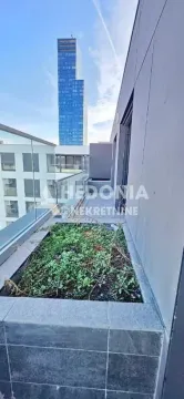 Terasa sa zelenom površinom i pogledom na visoku zgradu. - image 11
