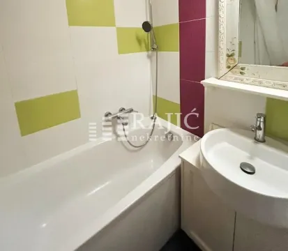 Small bathroom with a bathtub, washbasin, and mirror. - image 11