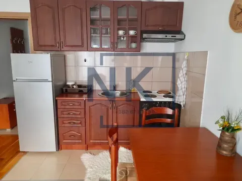 Small kitchen with wooden cabinetry, refrigerator, and a dining table. - image 3