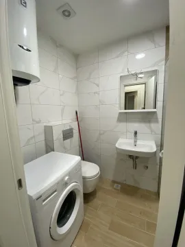 Bright bathroom with a washing machine, sink, and mirror. - image 17