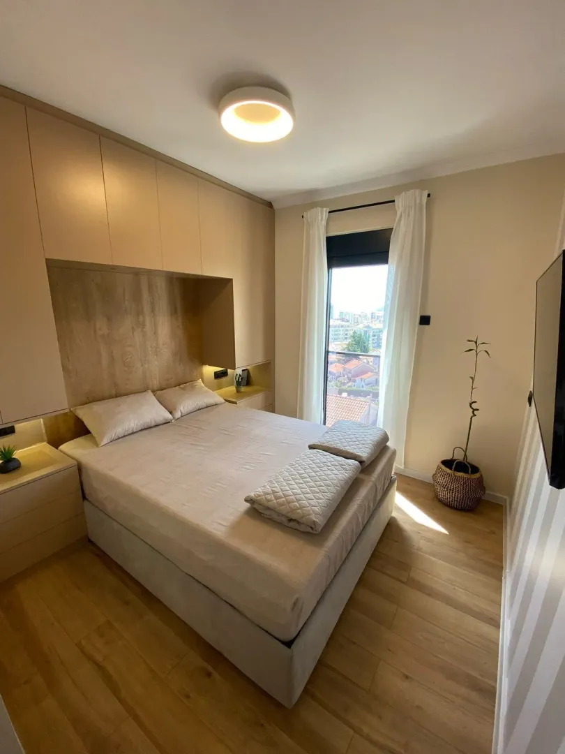 Modern bedroom with a double bed, fitted wardrobes, and a window view.