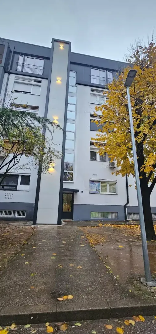 Pogled na ulaz i fasadu stambene zgrade.