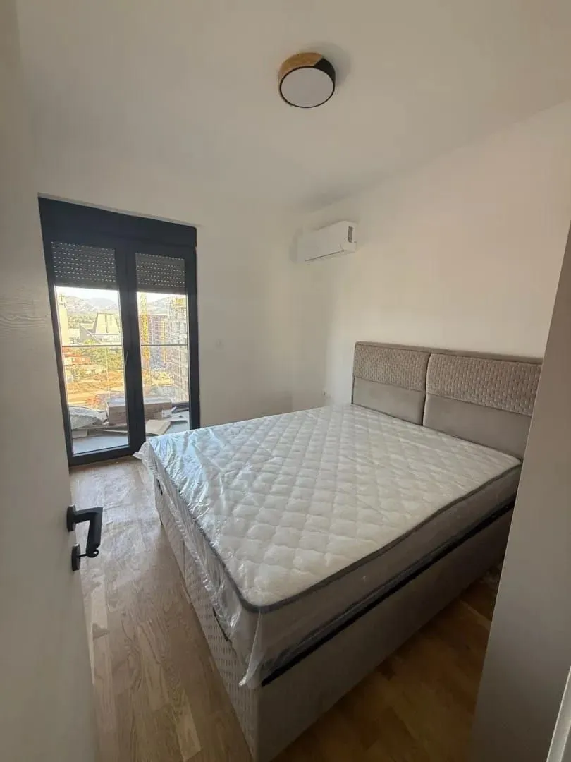 Bedroom with a double bed and a view through the window.