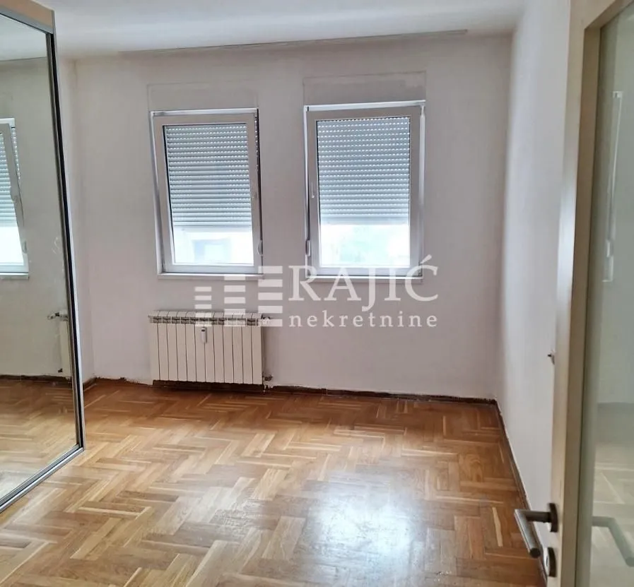 Empty room with parquet flooring and a built-in mirrored wardrobe.
