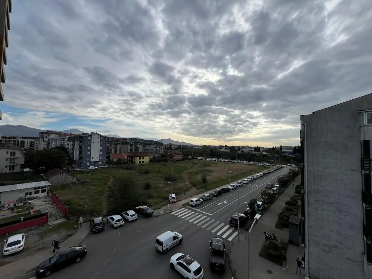 Pogled sa prozora na ulicu, parking i gradsko naselje.