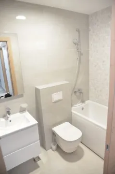Modern bathroom with a bathtub, toilet, and sink in light tones. - image 3