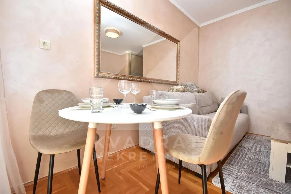 Living room with a dining table, sofa, and a large wall mirror.