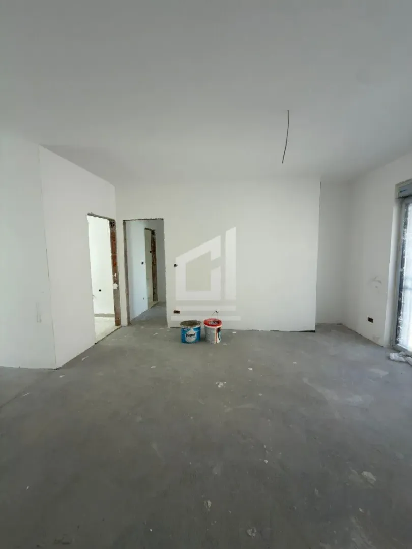 Prazna prostorija u toku renoviranja sa bijelim zidovima i kantama za farbu na podu.