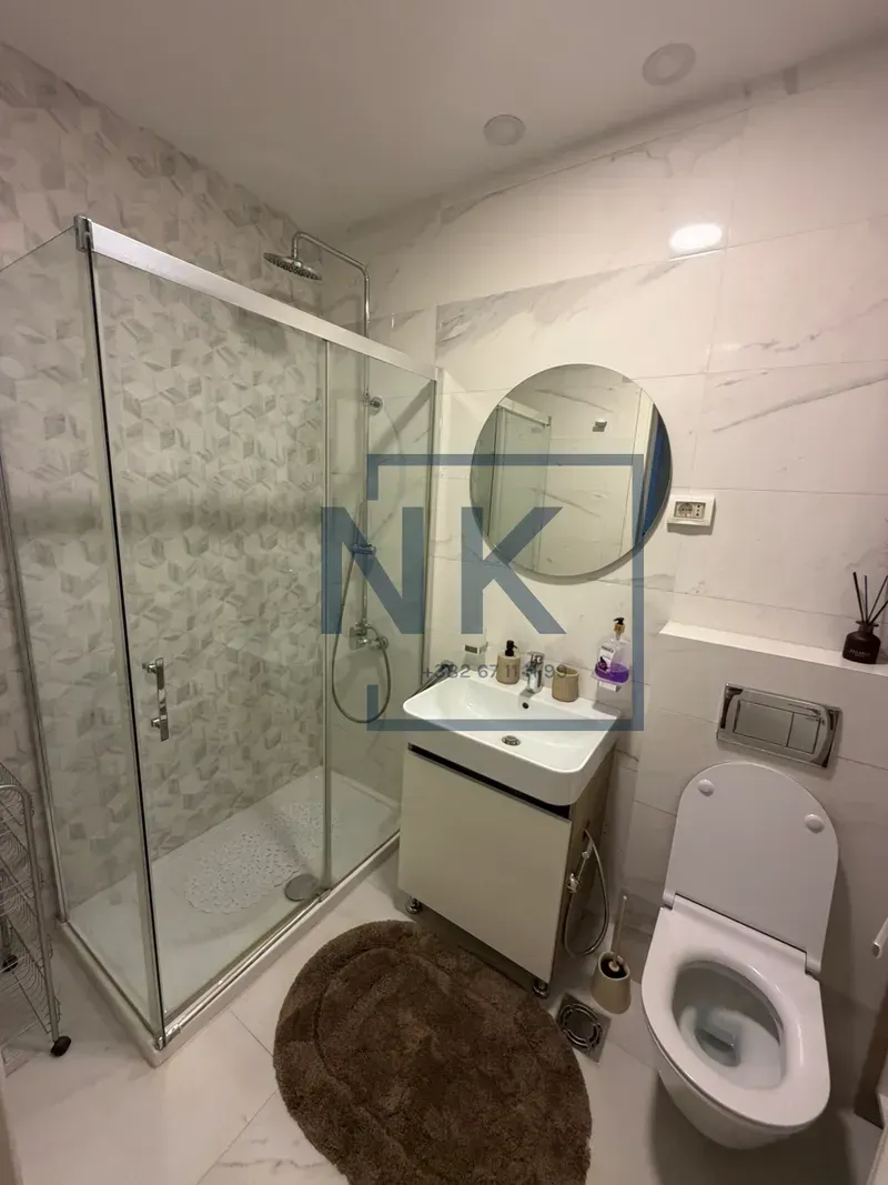 Modern bathroom with a shower cabin, washbasin, and toilet.