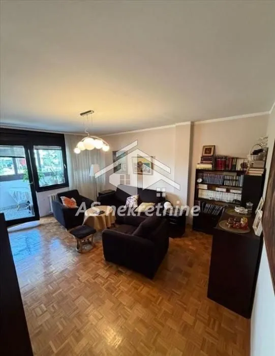 Living room with a seating set, bookshelves, and parquet flooring.