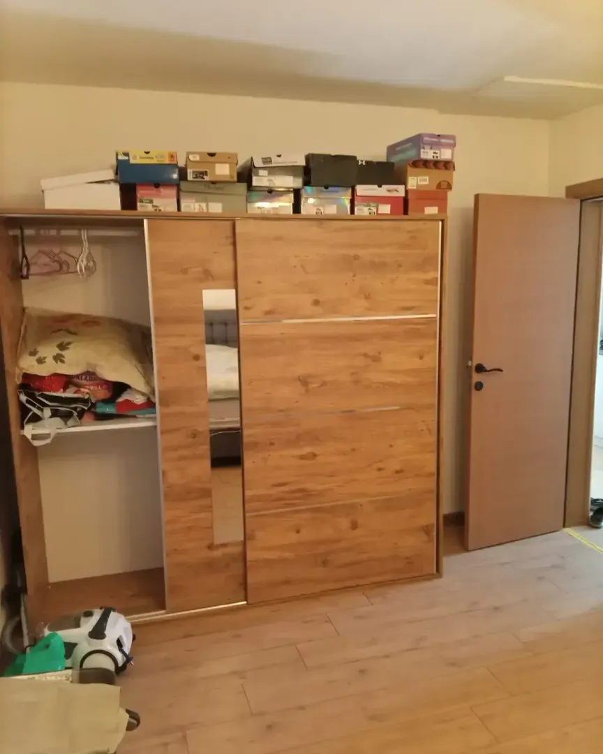 Bedroom with a wooden wardrobe and storage boxes on top.