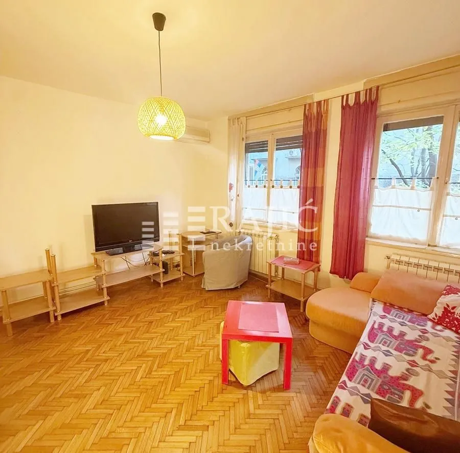 Living room with a sofa, television, and wooden flooring.