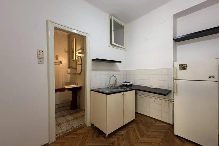 Small kitchen with a sink, refrigerator, and a view of the bathroom.