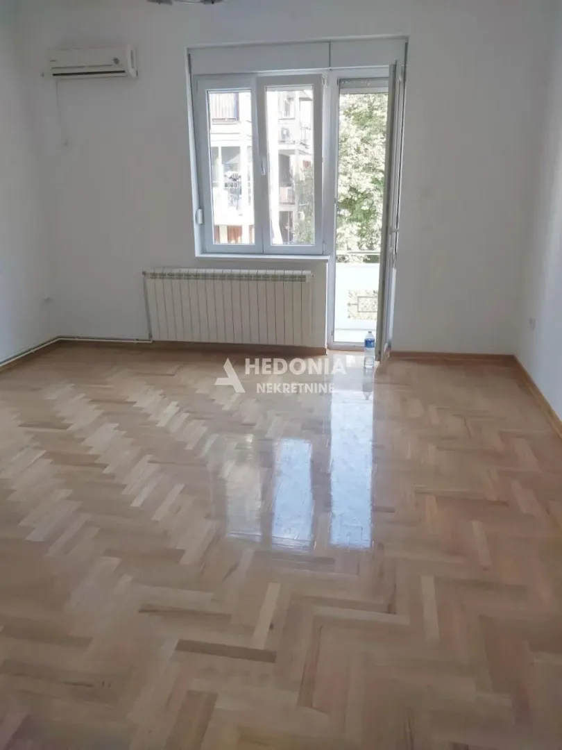 Prazna soba sa parketom i izlazom na terasu.