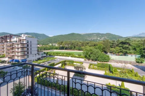 Pogled sa balkona na uređeno dvorište, zelenilo i planine u daljini. - image 15