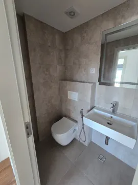 Manje kupatilo sa umivaonikom, WC šoljom i ogledalom obloženo keramičkim pločicama u zemljanim tonovima. - image 4