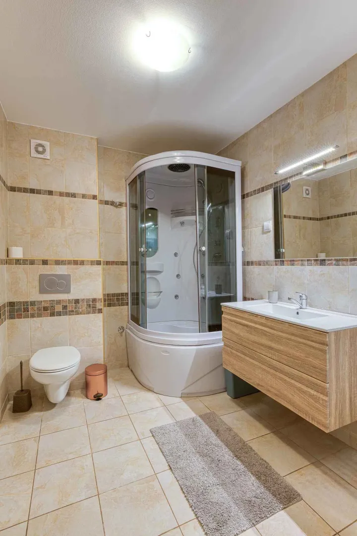Bathroom equipped with a shower cabin, vanity unit with sink, and toilet.