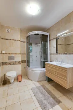 Bathroom equipped with a shower cabin, vanity unit with sink, and toilet. - image 16