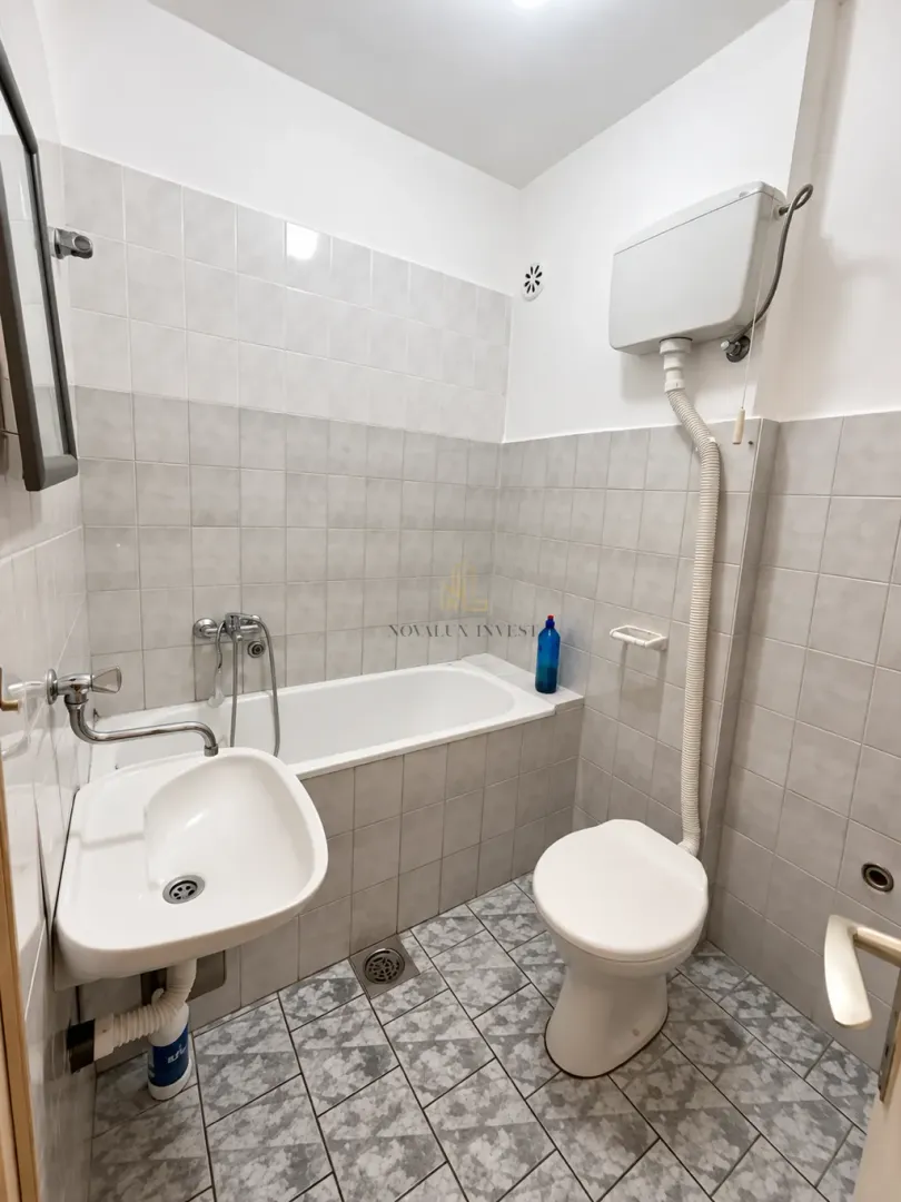 Small tiled bathroom with a bathtub, washbasin, and toilet.