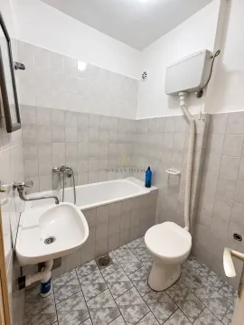 Small tiled bathroom with a bathtub, washbasin, and toilet. - image 7