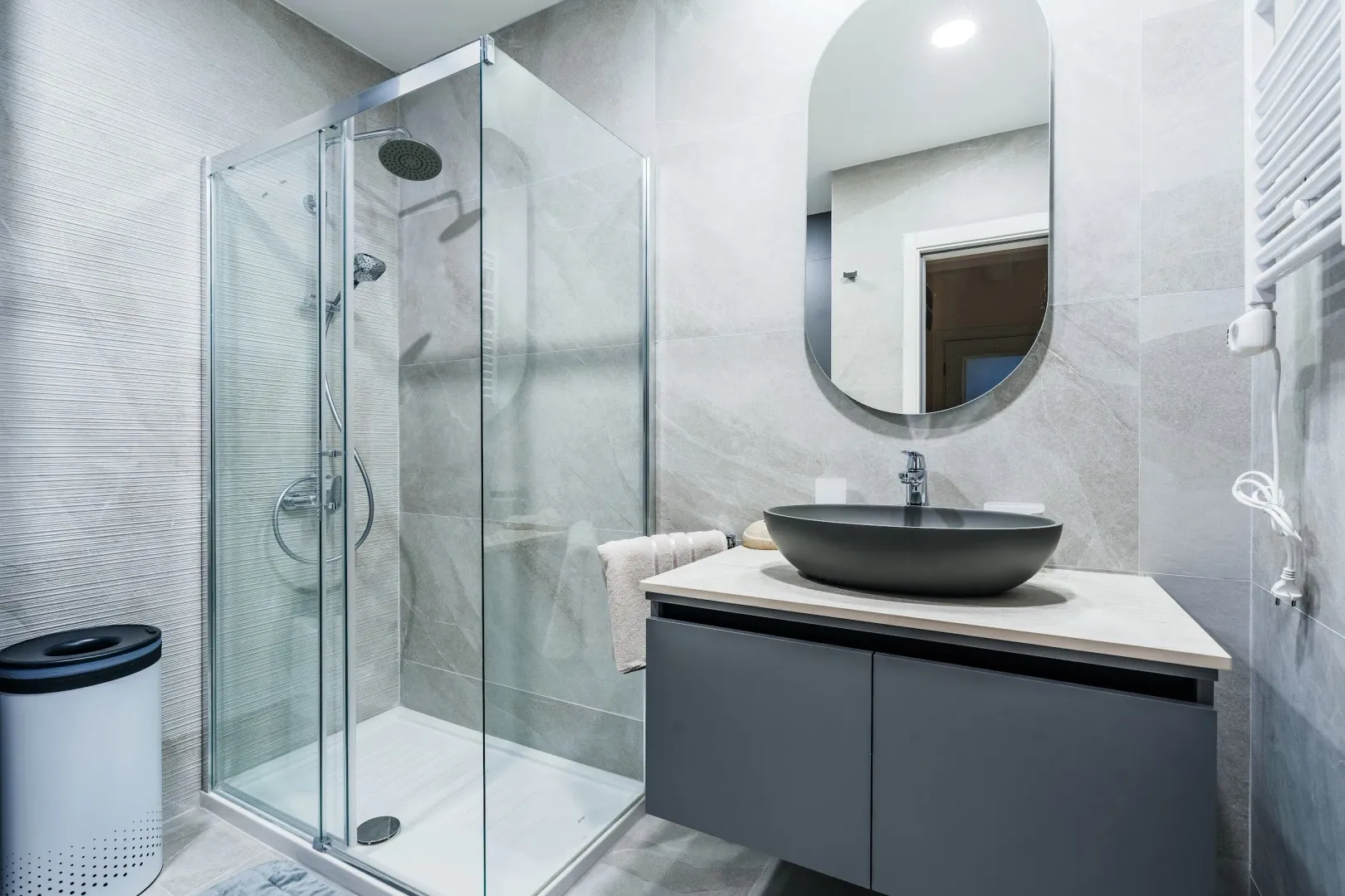 Modern bathroom with a walk-in shower, washbasin, and mirror.