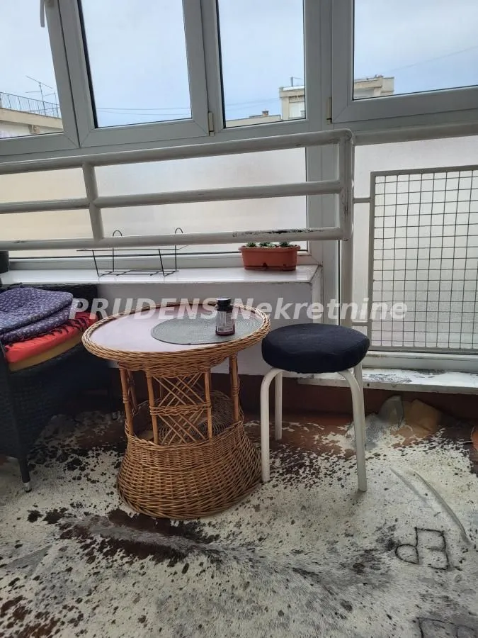 Manji zastakljeni balkon sa pletenim stočićem i stolicom.