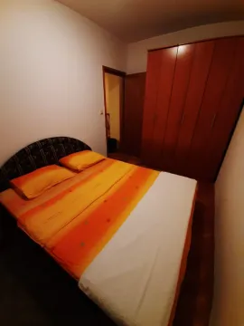 Jednostavna spavaća soba sa bračnim krevetom i velikim drvenim ormarom. - image 4