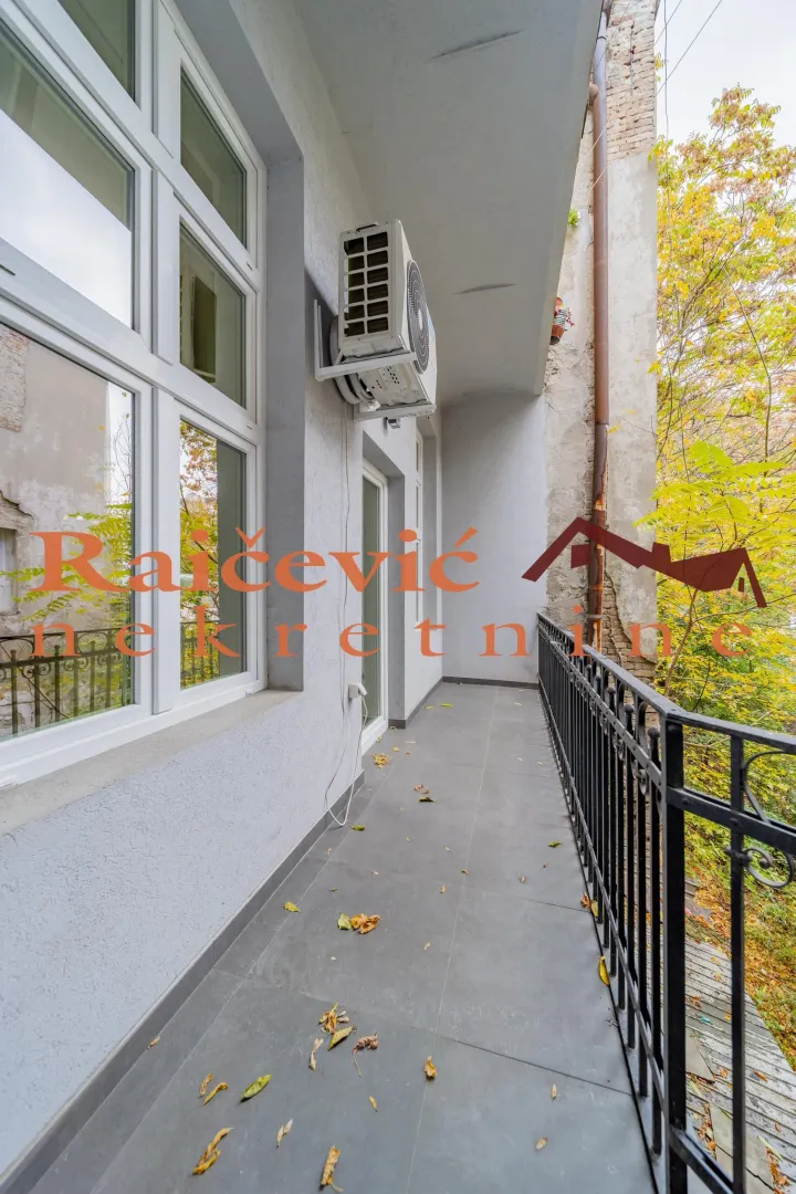 Long balcony with tile flooring and a metal railing along the building facade.