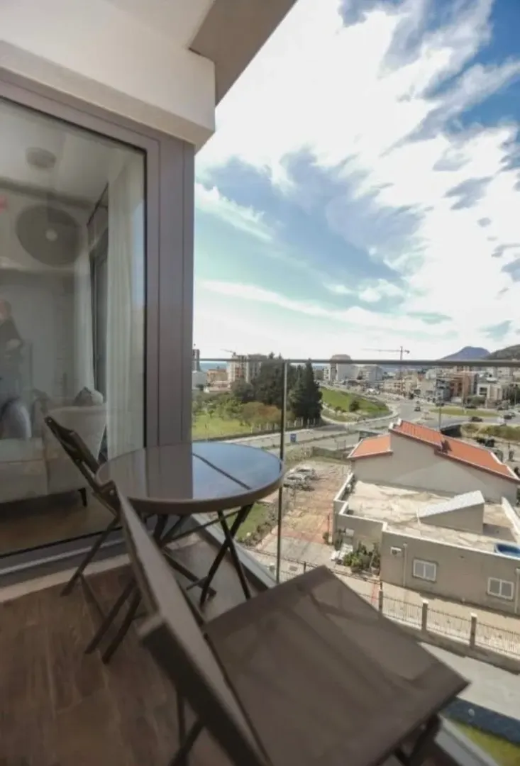 Small balcony with a table and chairs and a city view.
