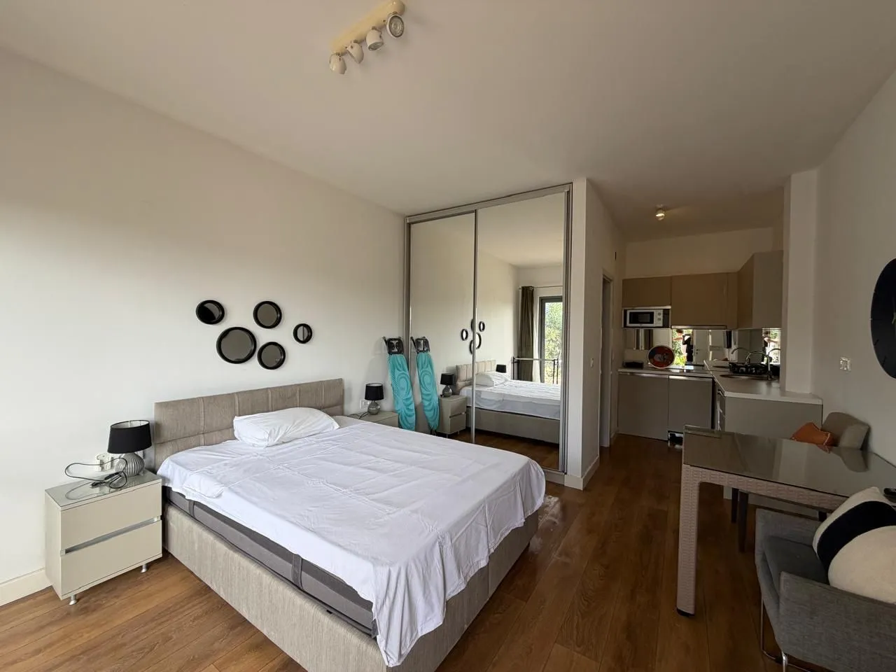Spacious bedroom with a double bed, large mirrored wardrobe, and kitchen area.