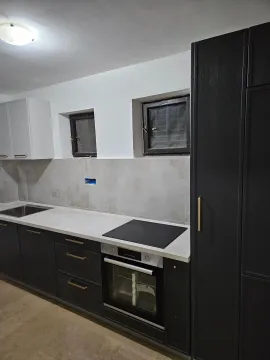 Modern kitchen with dark cabinetry and a built-in oven. - image 9