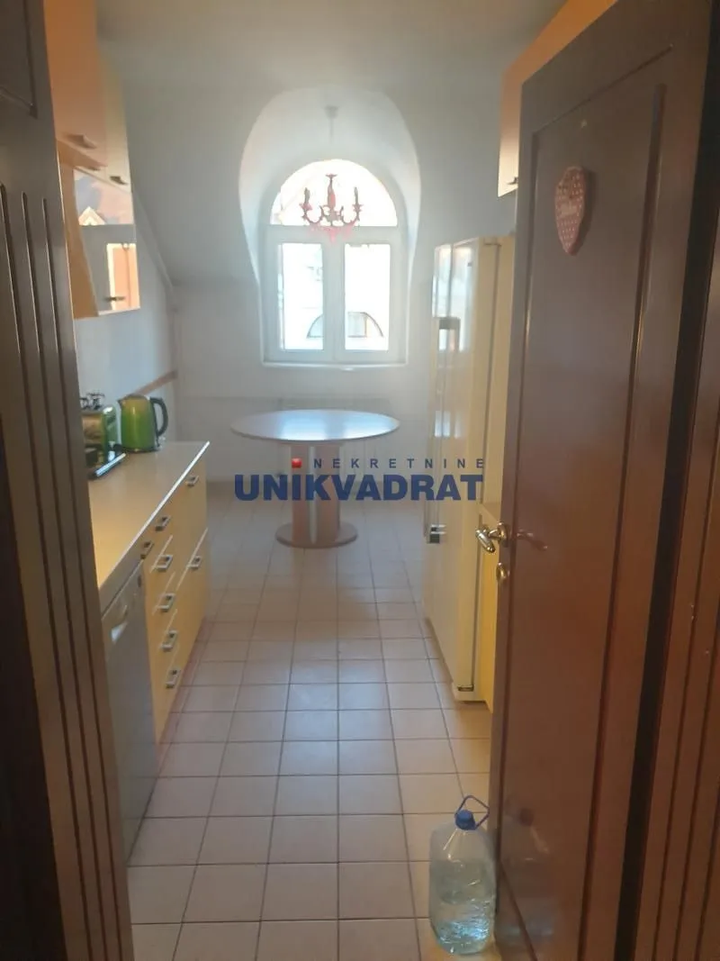 Manja kuhinja sa trpezarijskim stolom i prozorom na kraju prostorije.