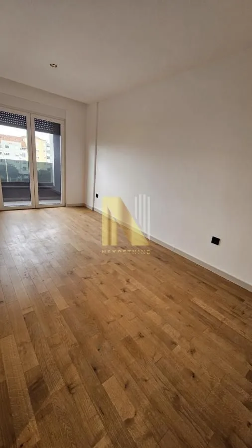Prazna soba sa parketom i izlazom na terasu.