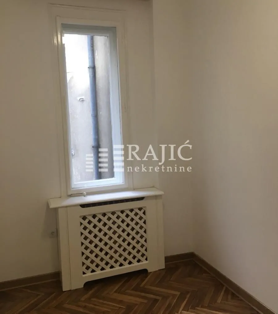 Empty room with a window and wooden flooring.