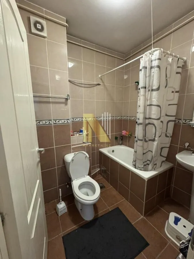 Kupatilo obloženo keramičkim pločicama sa kadom i wc šoljom.